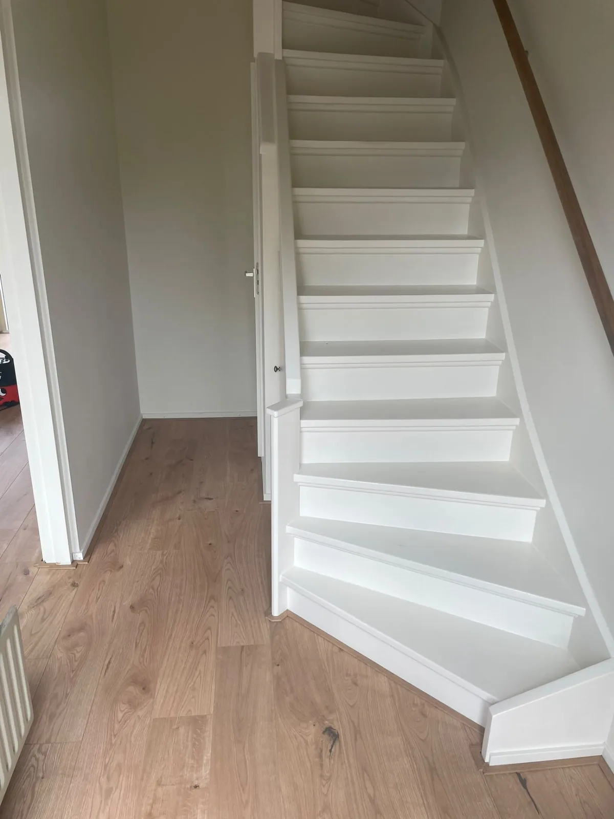 Wit afgewerkte trap en plinten in een hal