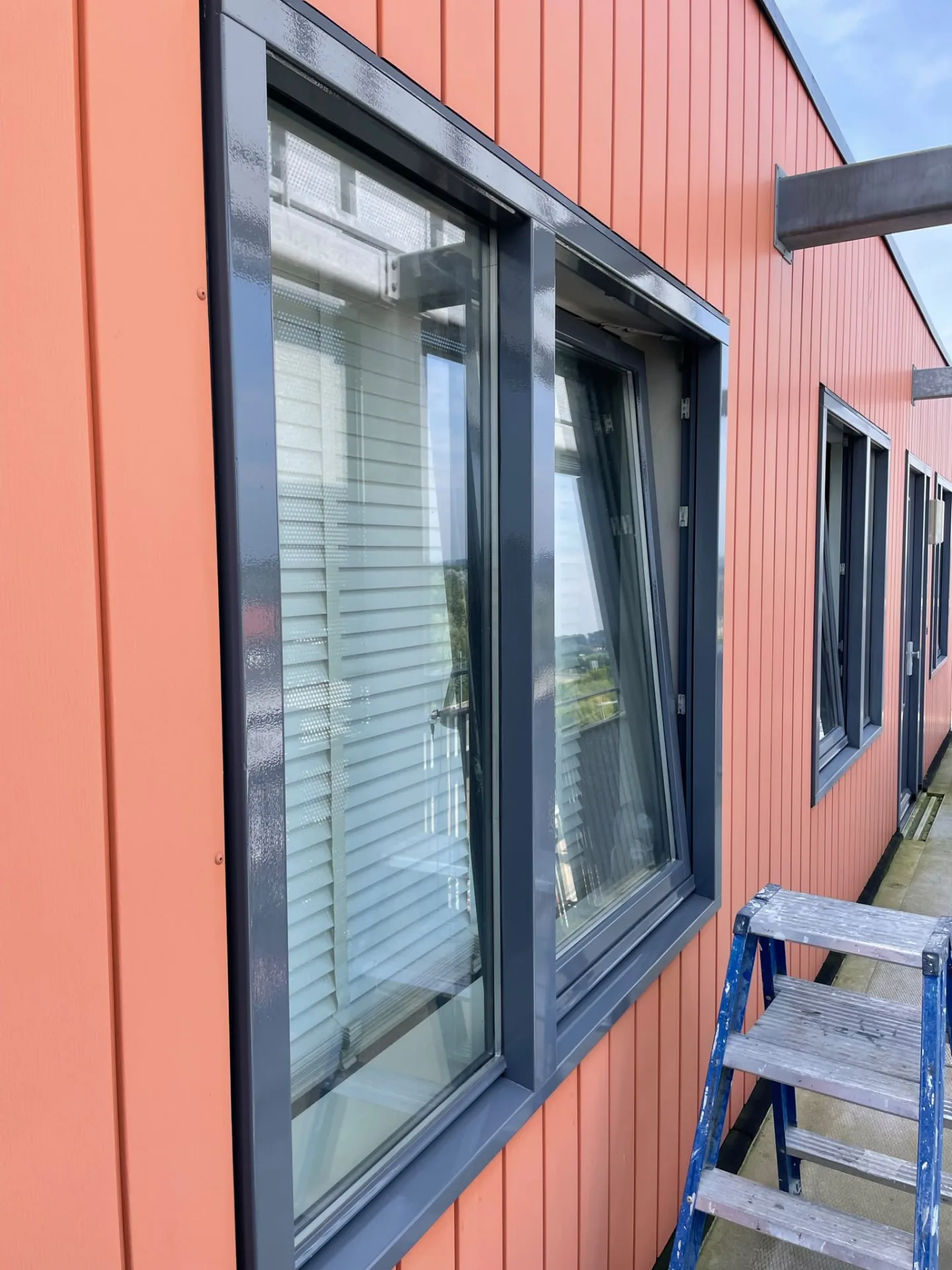 Buitenschilderwerk aan kozijnen en deuren langs de galerij van een flatgebouw