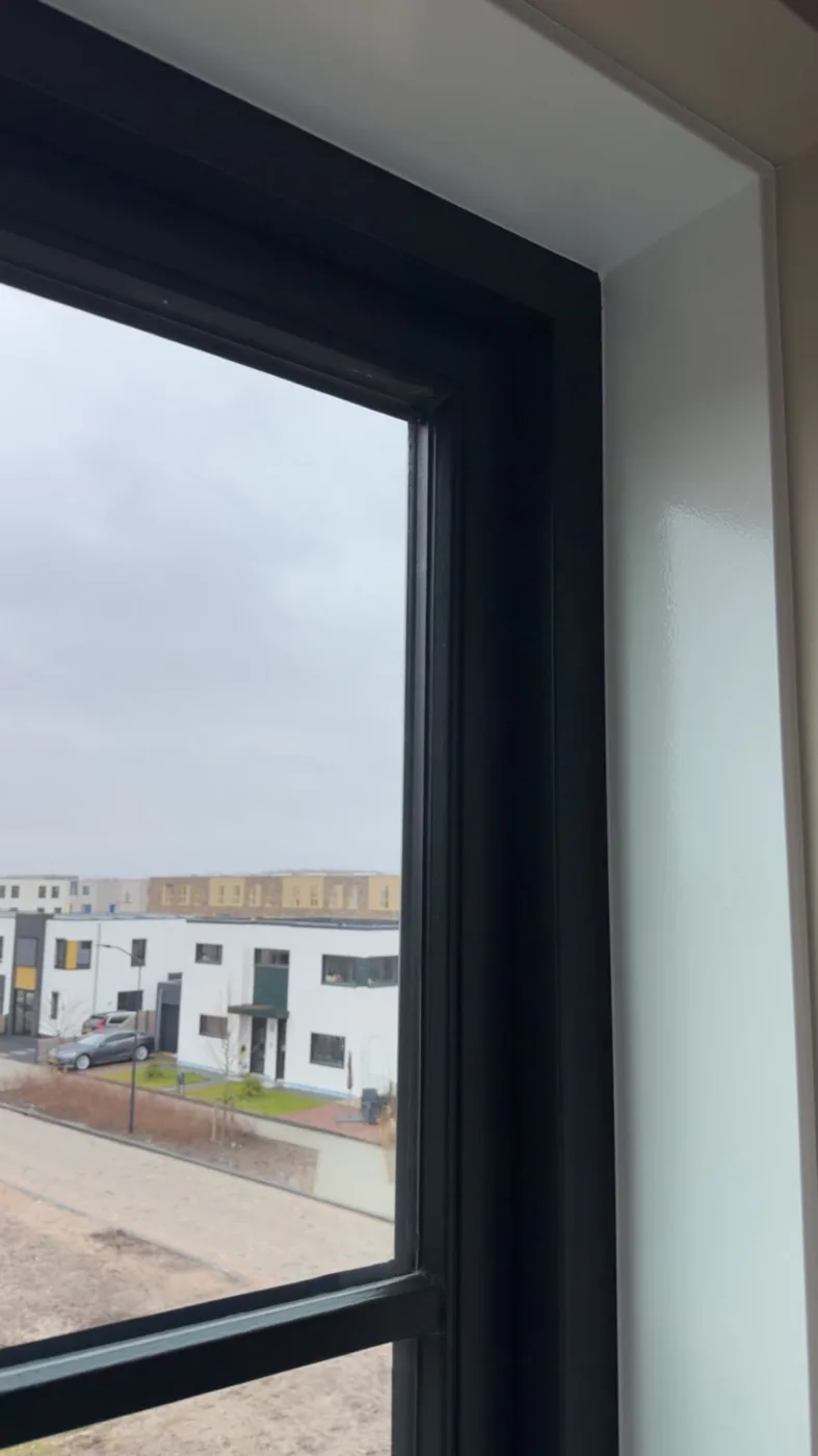 Zwart gelakt raamkozijn met strak afgewerkte witte binnenzijde