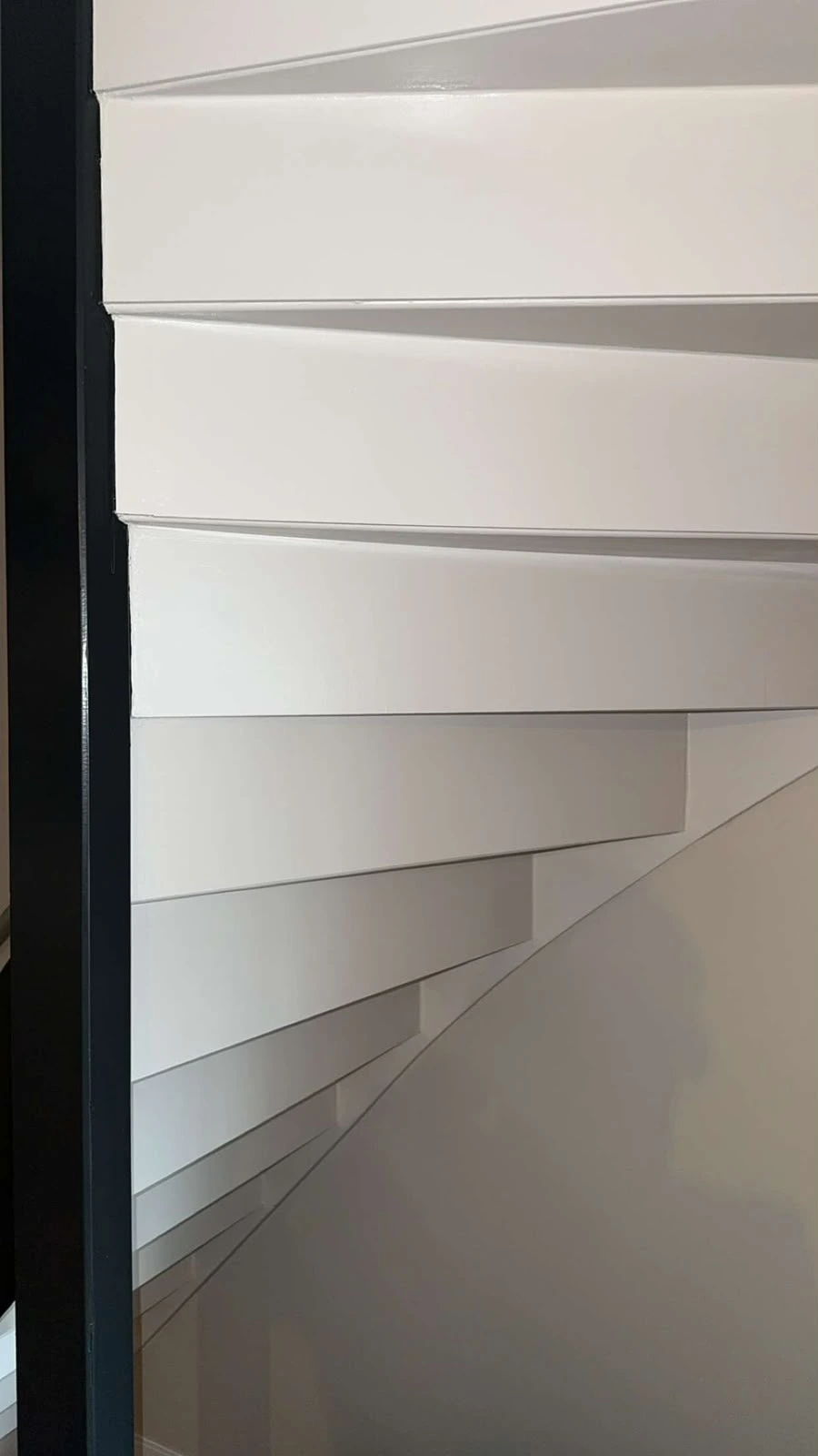 Trapdetail in hoogglans wit langs een zwart gelakt kozijn