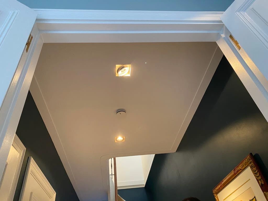 Wit lijstwerk en plafond tegen een diepe donkere wand